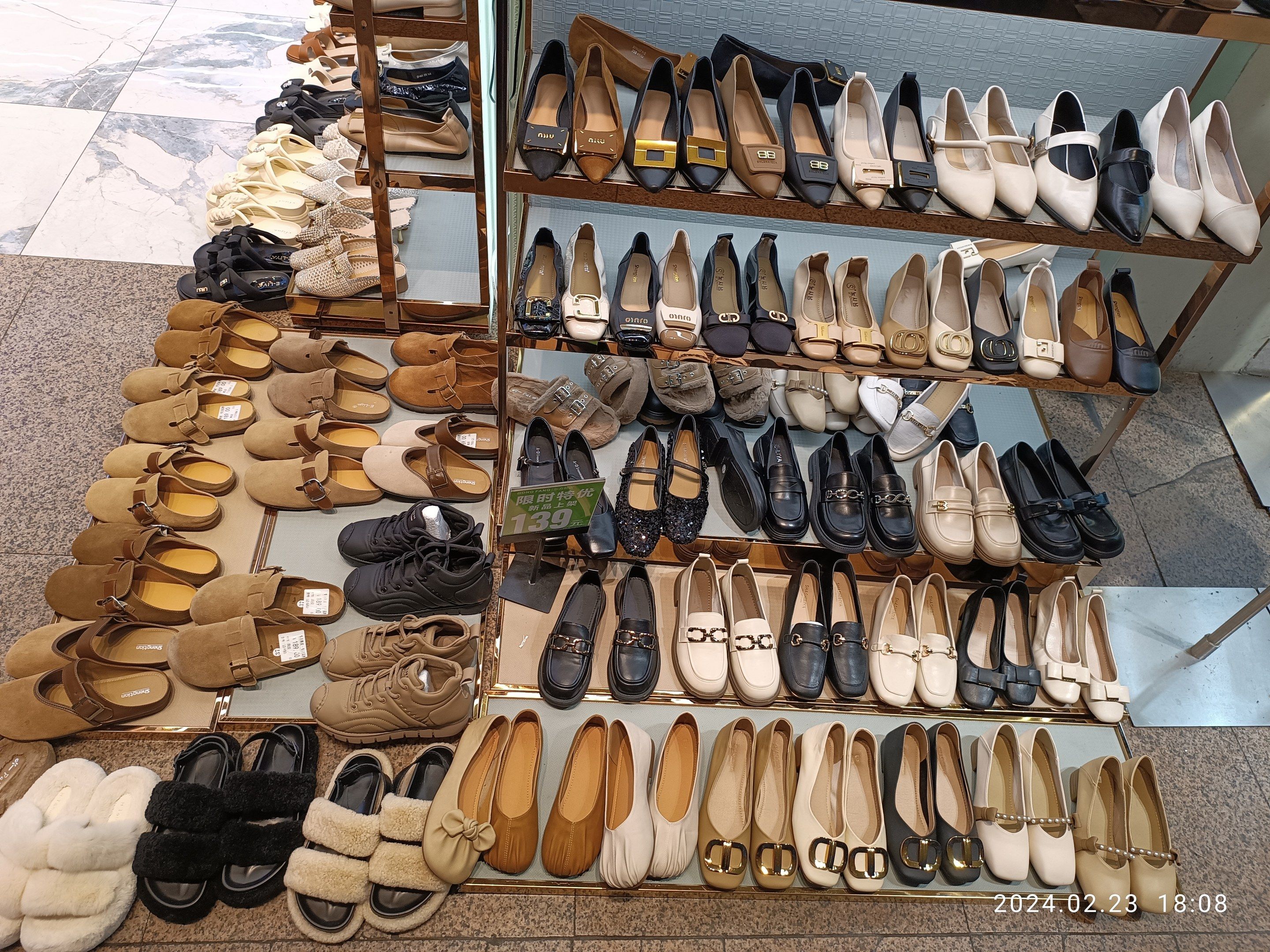 The image shows a display case filled with lots of different types of shoes, arranged in racks on...
