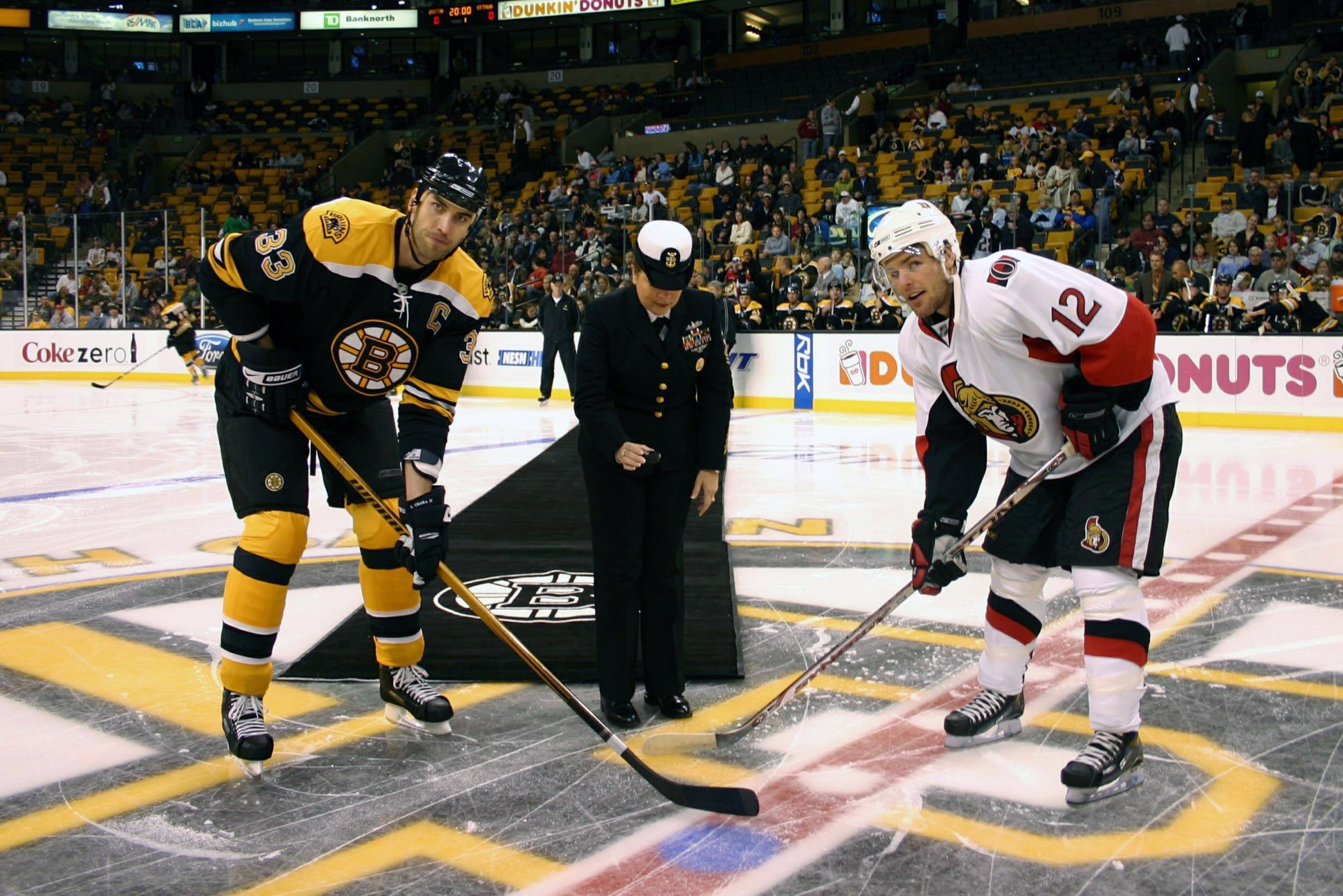 The image shows a hockey game between the Boston Bruins and the Ottawa Senators. We can see players...