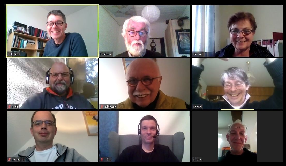The image shows a group of people on a video call, all wearing headsets and smiling. In the...
