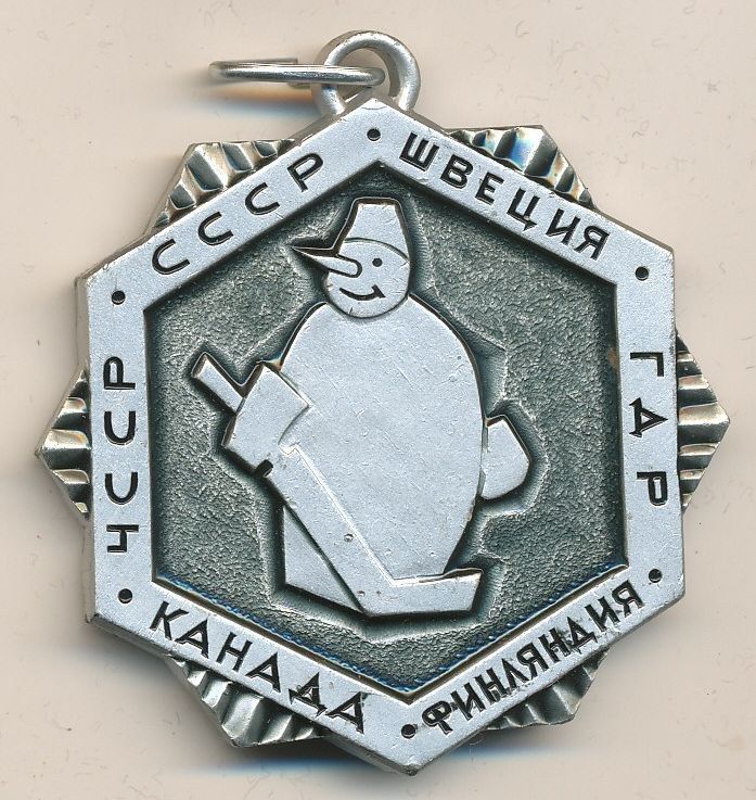The image shows a silver medal with a snowman on it. The medal is in the shape of a locket and has...