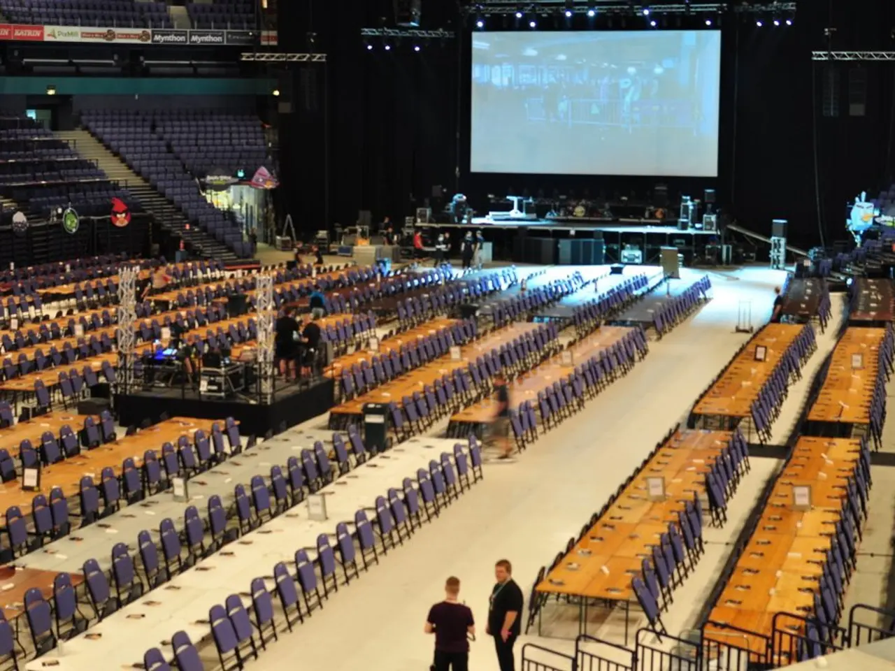 In this image I can see the floor, number of tables, number of chairs, few persons standing, few...