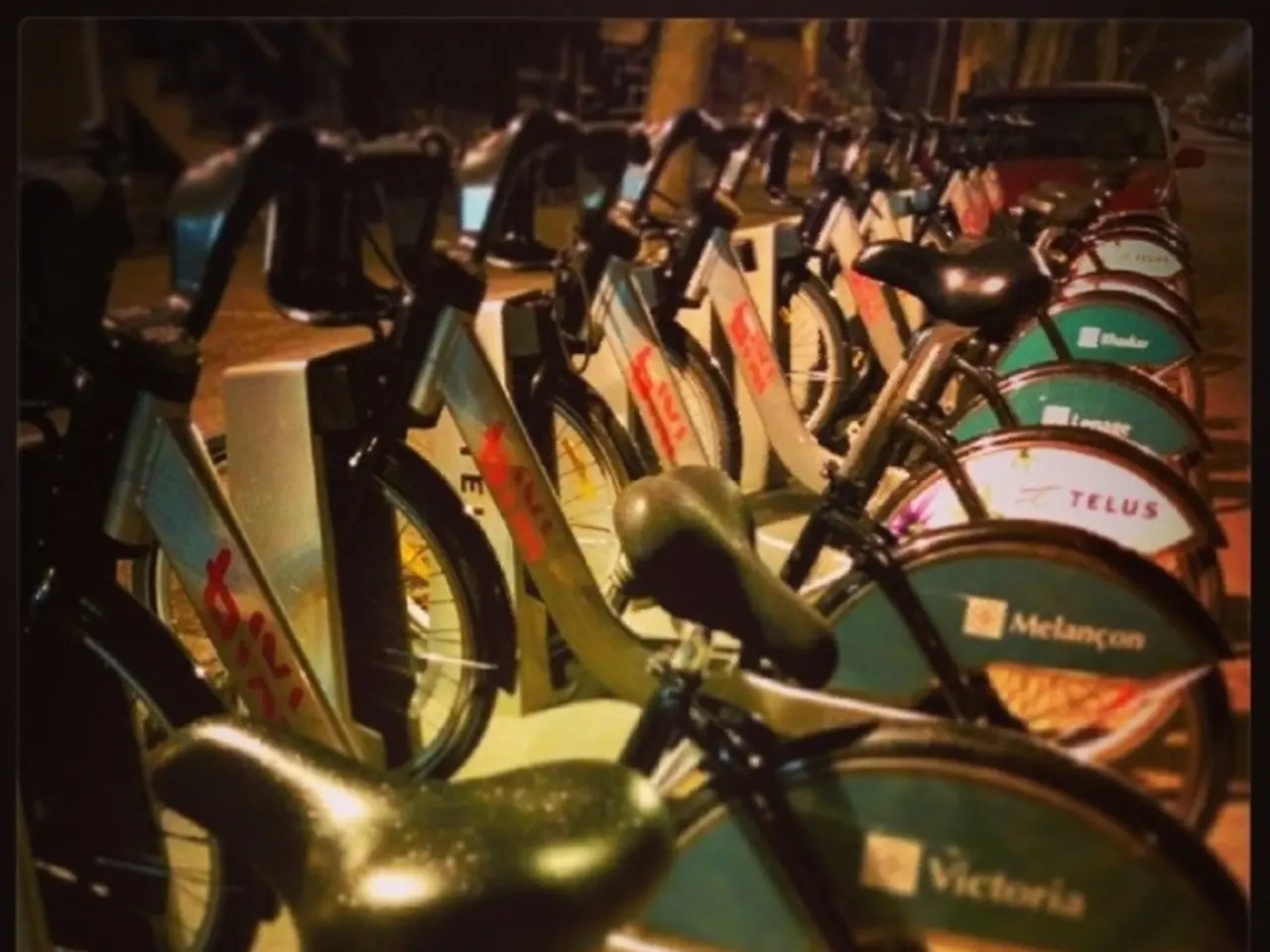 In the middle of the image we can see some bicycles. Behind the bicycles there is a vehicle.