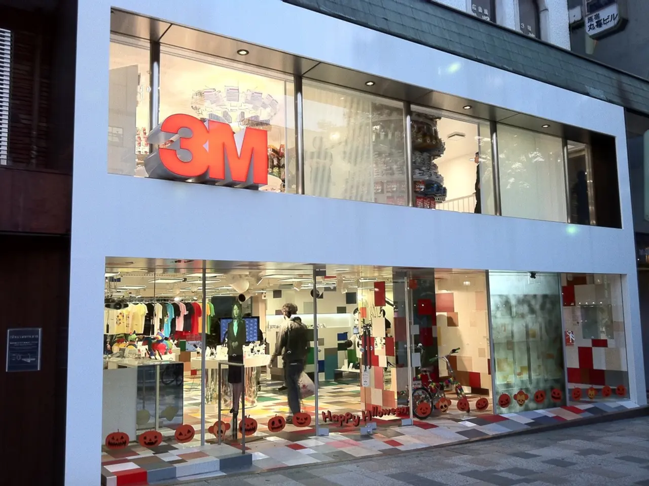 There is a building with a glass wall. Inside the building there are dresses hanged on the hangers....