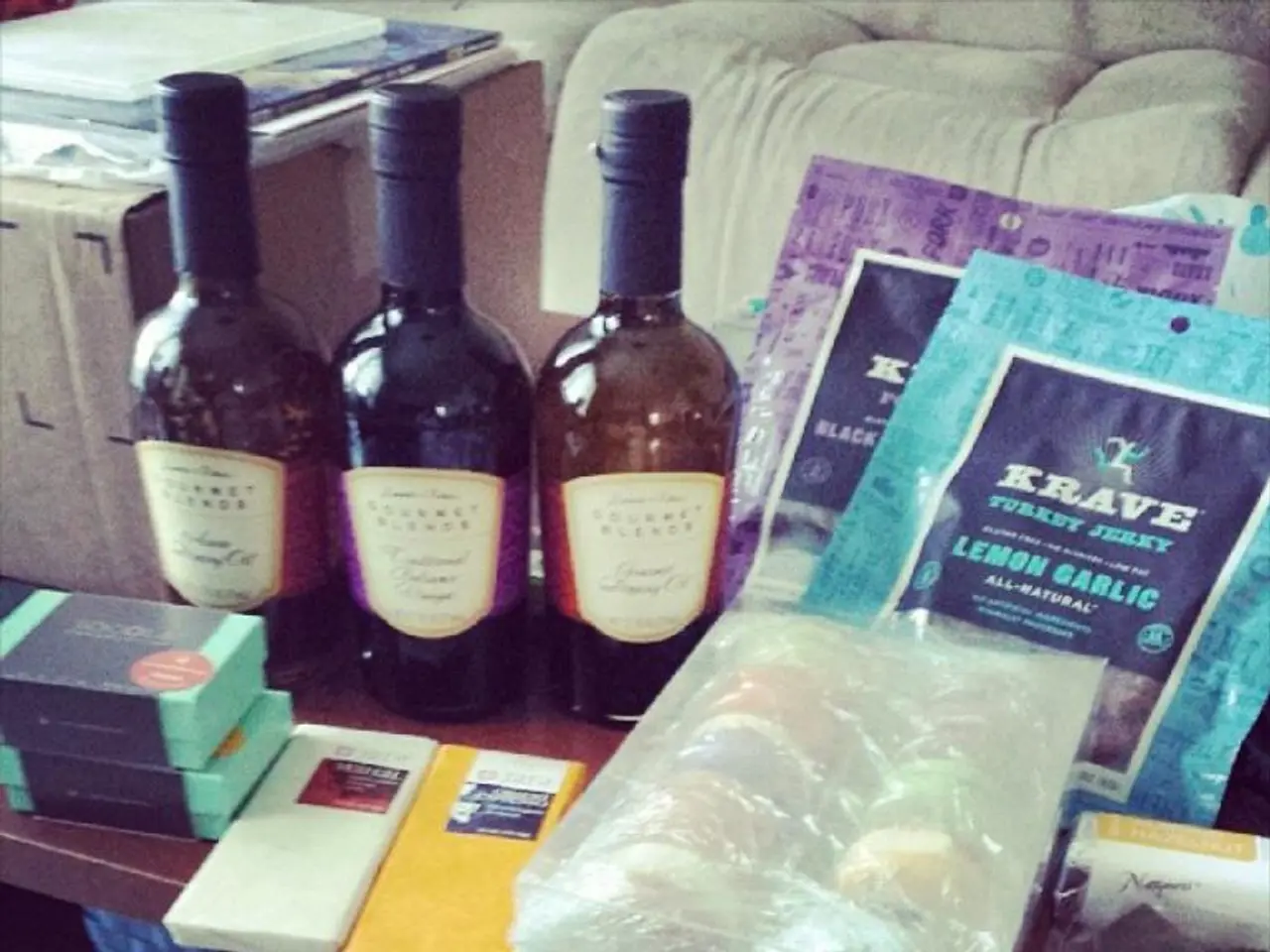 In the image there are few wine bottles on the table,beside them there are some food items wrapped...