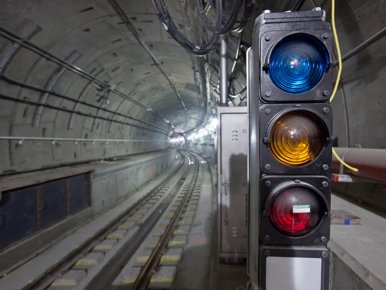 In this image we can see the track inside a subway. We can also see some wires, pipes, a container...
