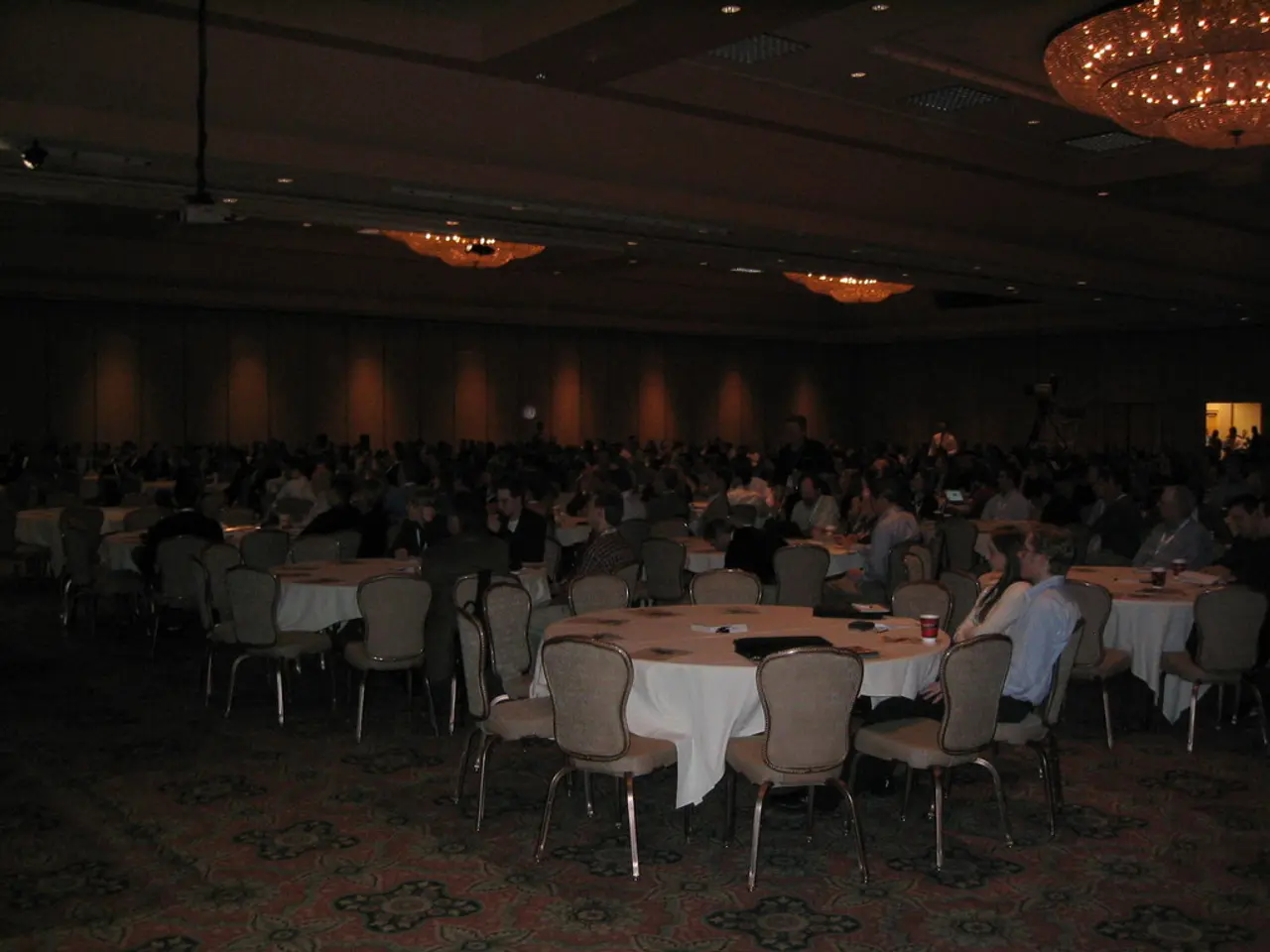 It looks like a dining hall. A group of people are sitting on the chairs around a round table.