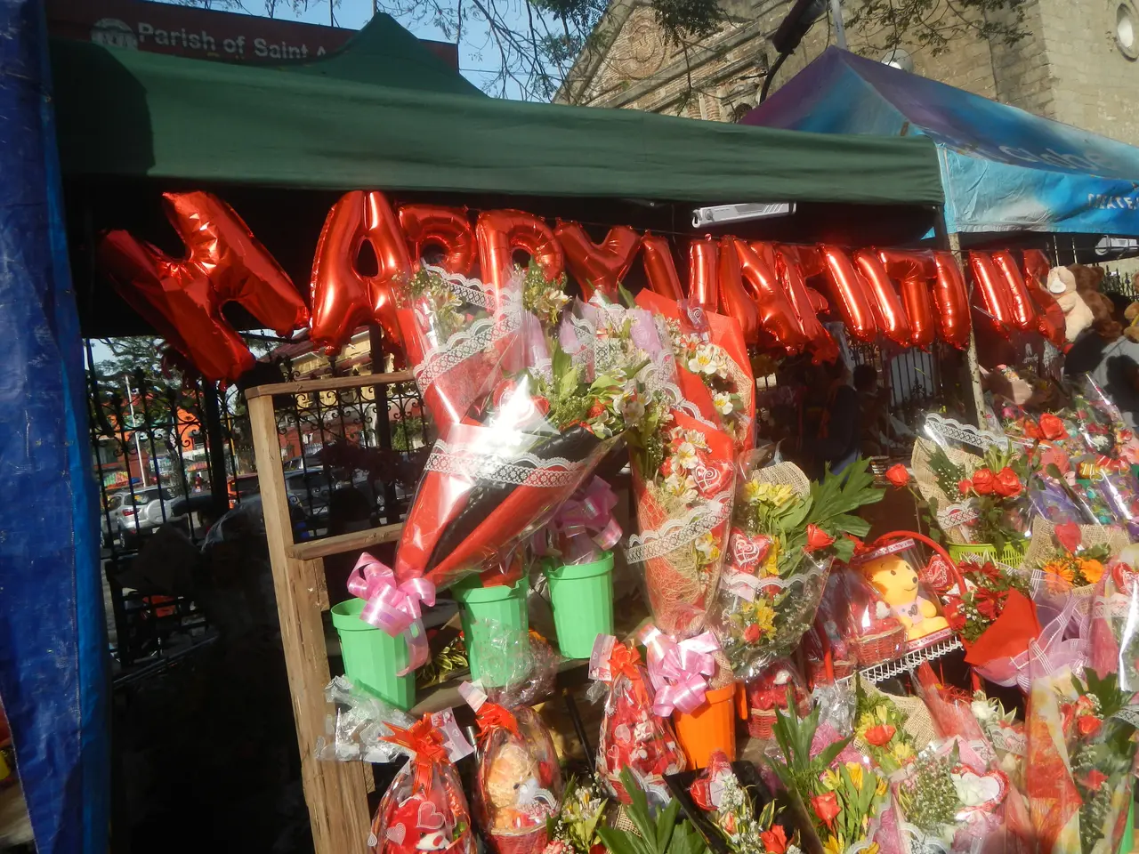 The image shows a flower shop with a variety of bouquets of flowers, teddy bears, buckets, and...
