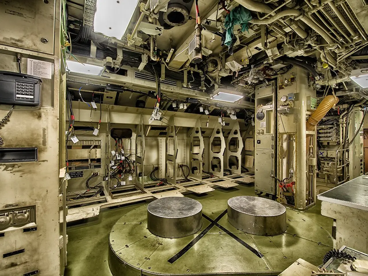 The image shows the inside of a submarine with a lot of equipment, including two round tables on...