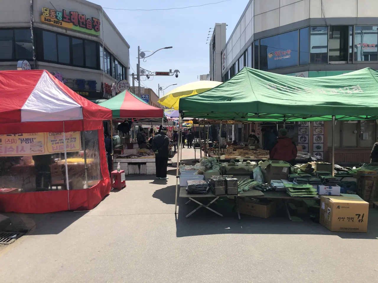 The image shows a bustling street market in Seoul, South Korea, with tents set up on the side of...