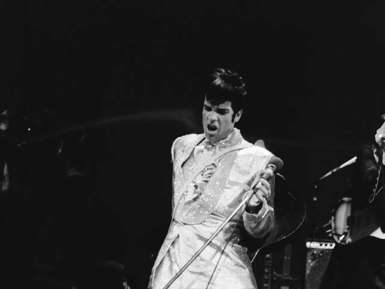 The image shows Elvis Presley performing on stage at the Apollo Theater in Las Vegas, Nevada. He is...