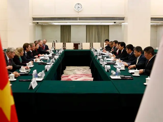 In this image we can see people sitting. There are tables. On the table there are name boards,...