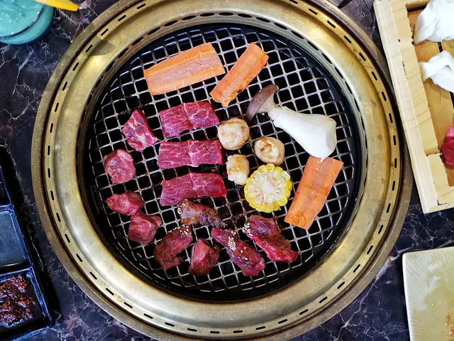 In this picture I can see there is a grill and there is meat, corn, carrots, mushroom placed on it....