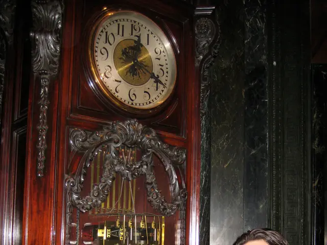 In this image there is a couple standing with a smile on their face, behind them there is a clock...