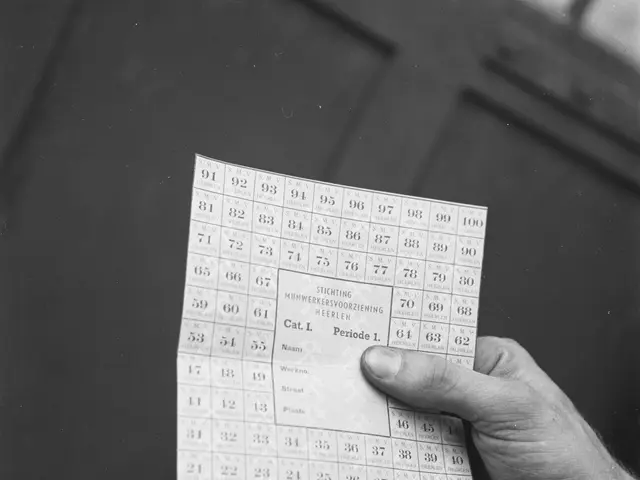 The image shows a person holding a bingo card in their hand, with a table in the background. The...