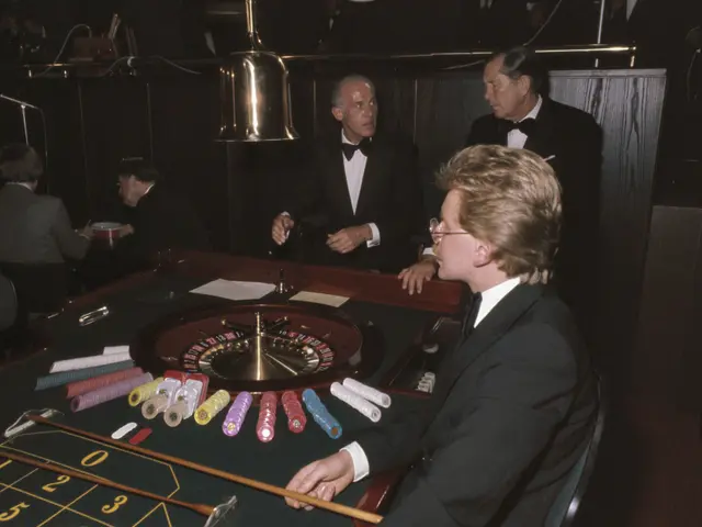The image shows a man in a tuxedo playing roulette at a casino. He is sitting in a chair at the...