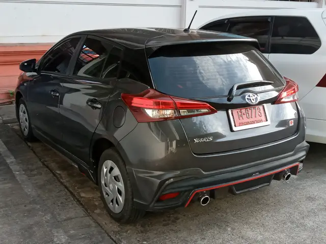 The image shows a Toyota Yaris Hatchback 1.5 G AT parked on the road with a wall in the background....