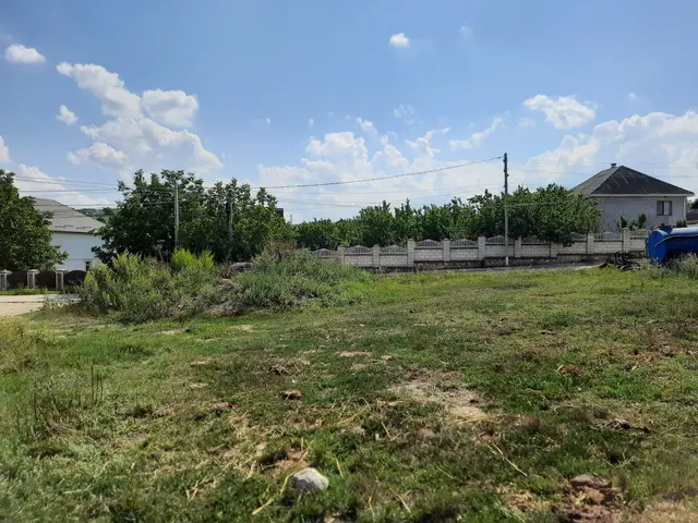 The image shows a vacant lot in the middle of a grassy field with a blue truck parked in front of...