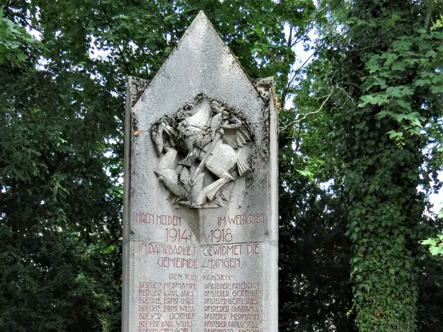 The image shows a monument in the middle of a forest, with text inscribed on it. Surrounding the...