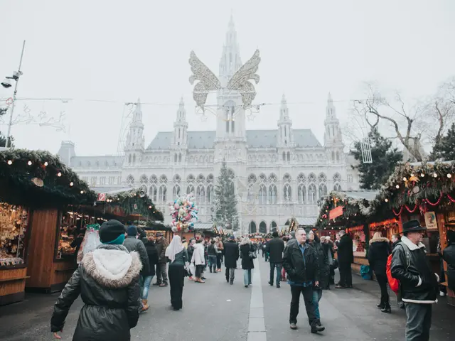 The image shows a bustling Christmas market in Vienna, Austria. There are many people walking...