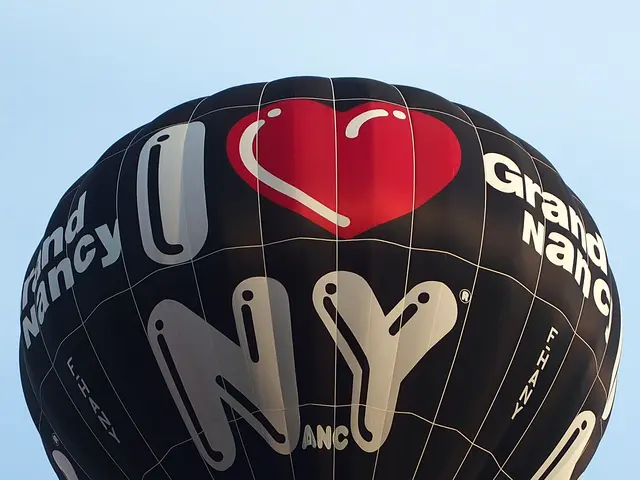 The image shows a hot air balloon with the words "I Love NYC" written on it, floating in the sky....