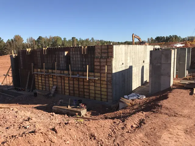 The image shows a construction site with a house being built in the middle of it. The house is made...