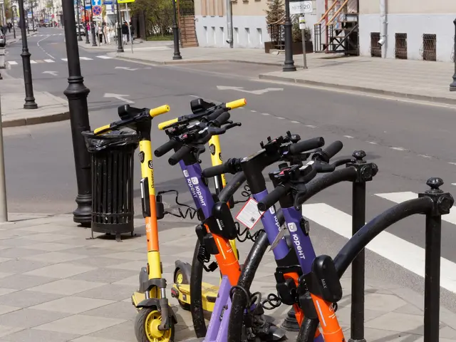 The image shows a row of electric scooters parked on the side of a street, with a dustbin in the...