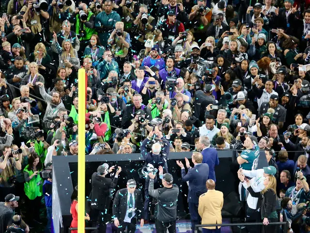 The image shows a group of people standing on top of a stage, some of them holding cameras and...