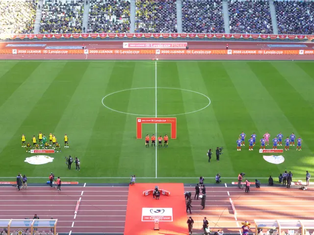 The image shows a group of people standing on top of a soccer field, surrounded by a stadium filled...