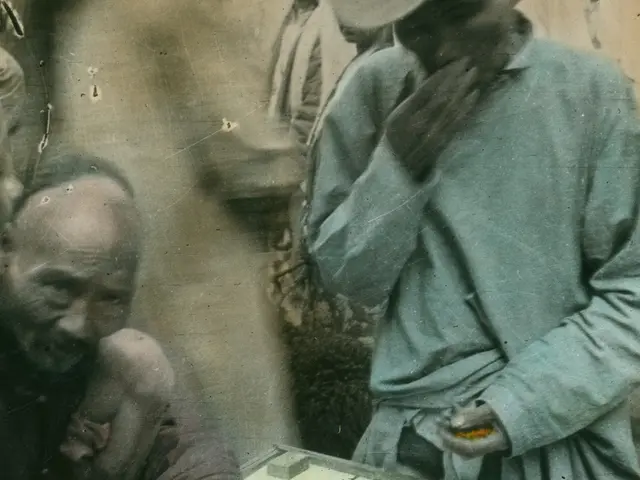 The image shows an old photo of two men playing a game of checkers. One of the men is wearing a cap...