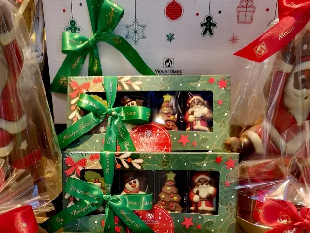 The image shows a table topped with lots of different types of chocolates, including boxes with...