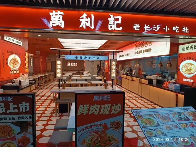 The image shows a Chinese restaurant with tables and chairs in front of it. There are boards with...