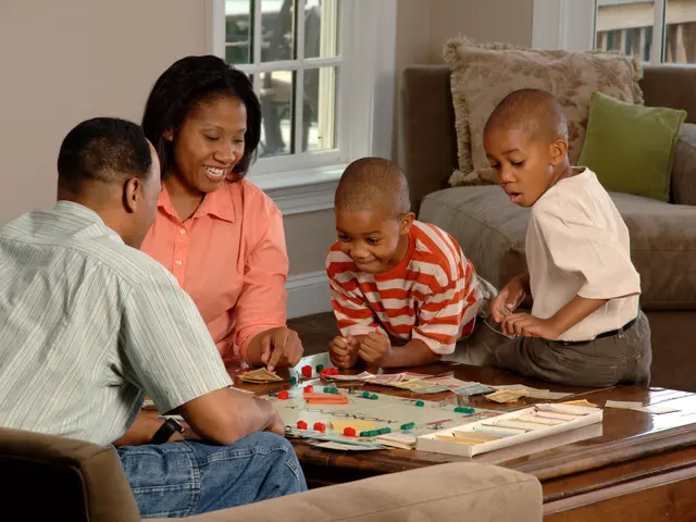 The image shows a family of four - a man, woman and two boys - sitting on a couch playing a board...
