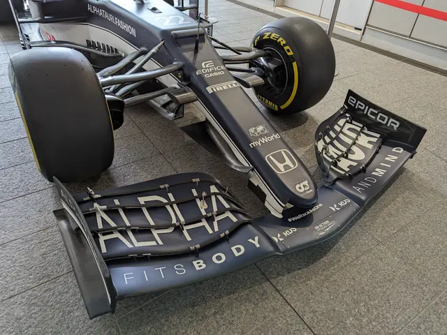 The image shows a McLaren MP4-31 Formula 1 car on the floor of the McLaren Museum, with a wall in...