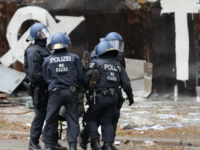 The image shows a group of police officers standing in front of a building with graffiti on it....