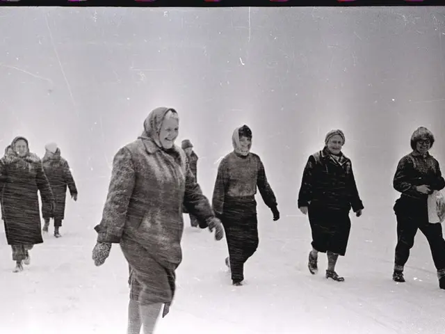 The image shows a group of people walking across a snow covered field, all wearing coats and caps....