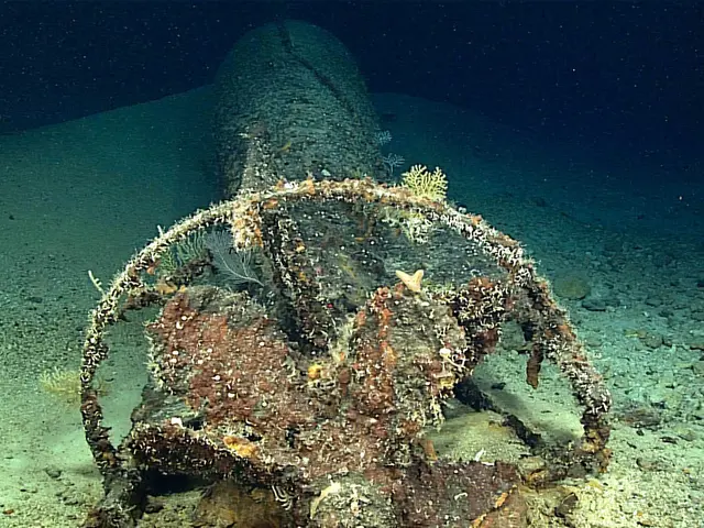 The image shows an underwater scene with a large piece of metal, which appears to be a wreck, lying...