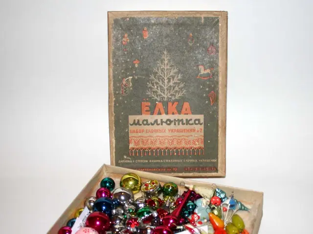 The image shows a box filled with lots of colorful Christmas ornaments sitting on top of a table....
