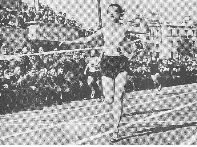 The image shows a black and white photo of a woman running on a track in front of a crowd of...