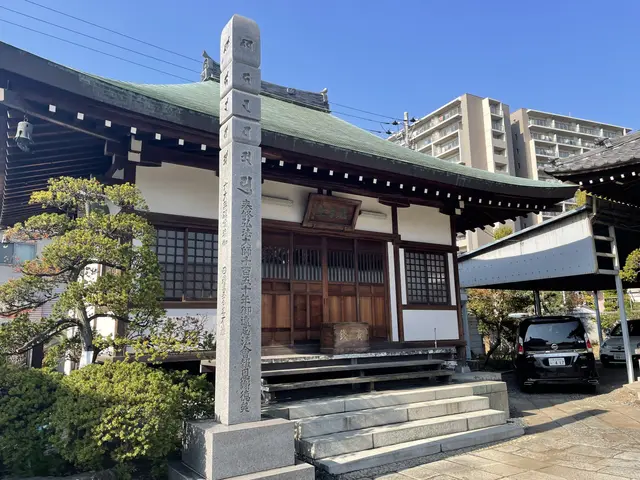 The image shows a large building with a green roof and a car parked in front of it, surrounded by...