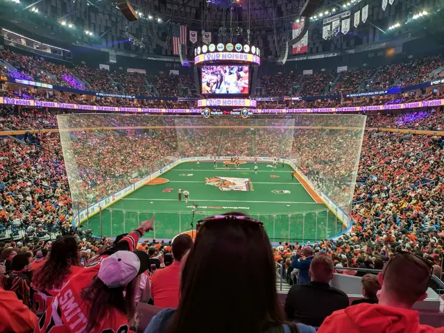 The image shows a large crowd of people watching a hockey game in a stadium. The stadium is filled...