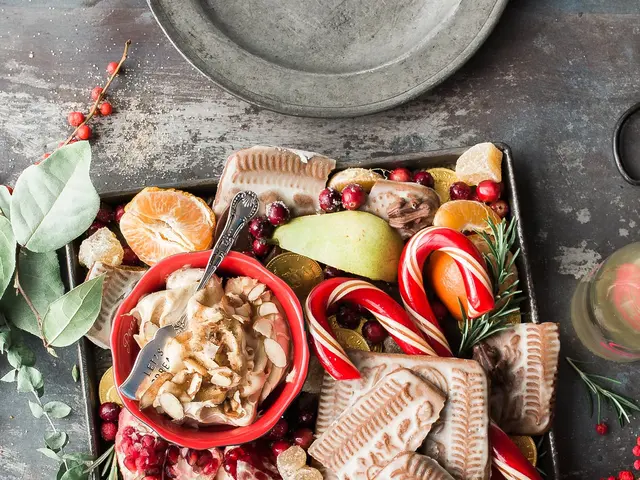 The image shows a tray filled with a variety of Christmas treats, including pomegranates, candies,...