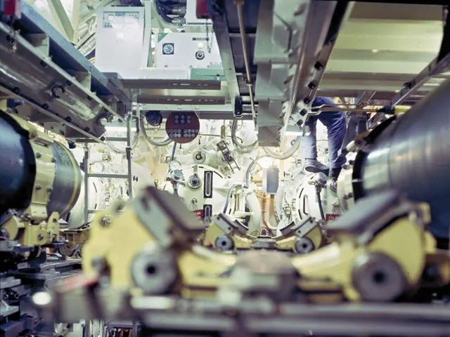 The image shows a man standing on top of a machine in a room, surrounded by various machines and...