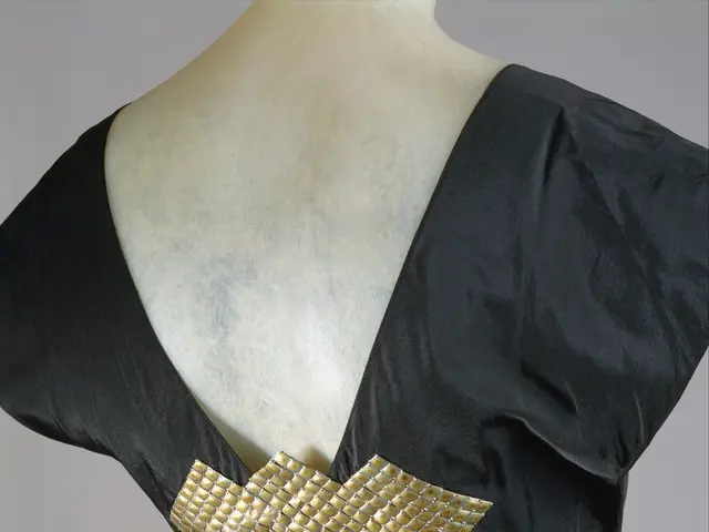 The image shows a mannequin wearing a black evening dress with a gold belt cinching the waist. The...