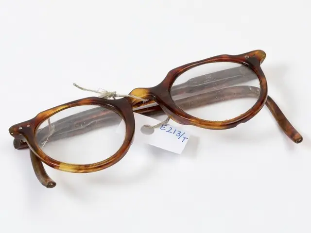The image shows a pair of glasses sitting on top of a white surface, with a tag attached to them...