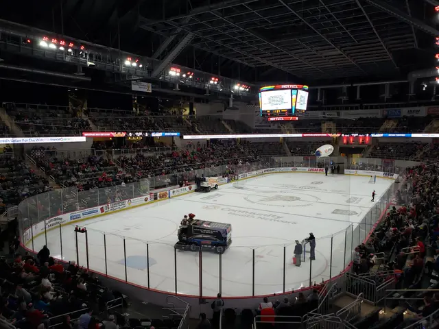The image shows a hockey game being played in a large arena, with vehicles on the ice and people...