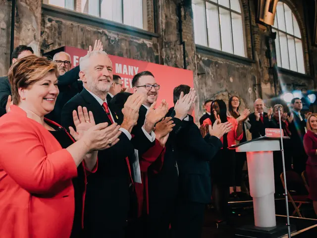 The image shows a group of people standing in front of a crowd, clapping their hands in...