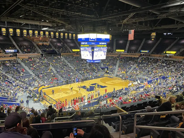 The image shows a large arena filled with lots of people watching a basketball game. There are...