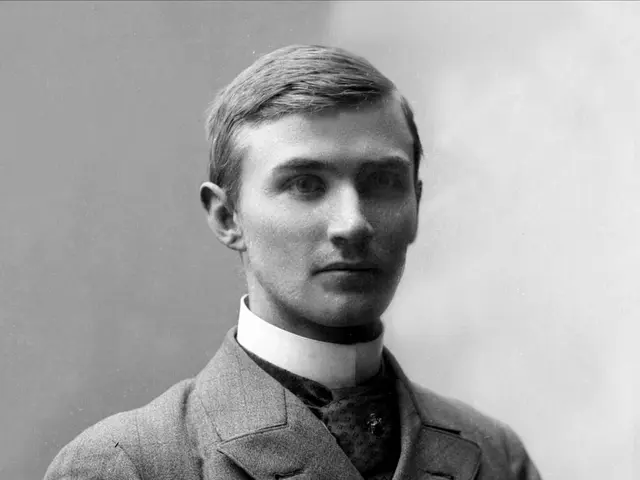 The image shows a black and white photo of a man in a suit and tie, believed to be the founder of...