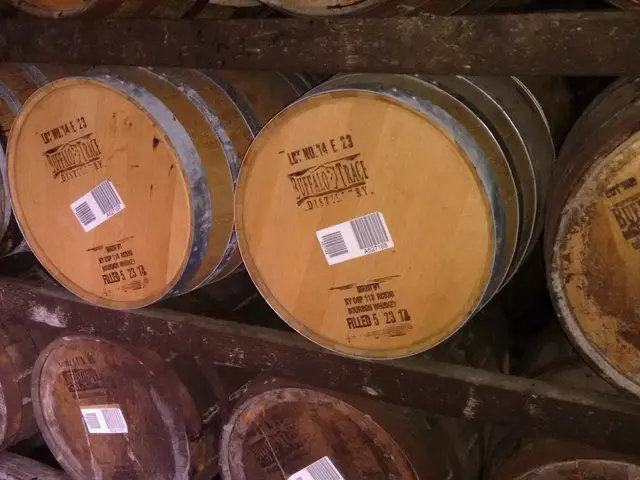 The image shows barrels of whiskey stacked on top of each other in a rack. The barrels are made of...