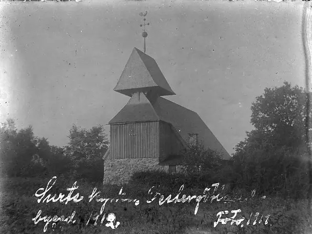 The image shows an old black and white photo of a church with a steeple, surrounded by trees and...